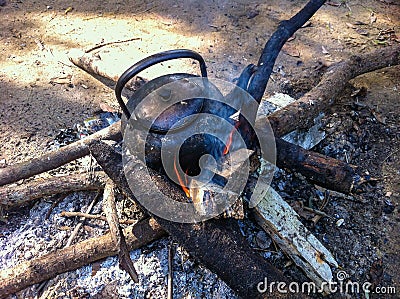 Close up of old, dirty teapot with water warming on the fire in touristic camp. Stock Photo