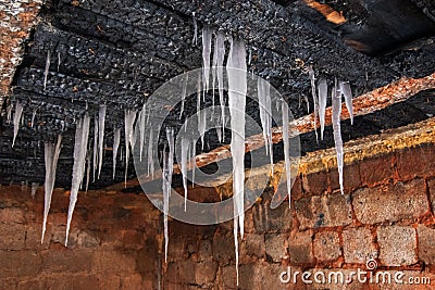 Close-up of an old house with a charred ceiling from which white icicles hang Stock Photo