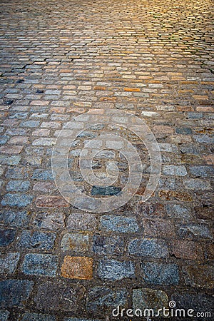 Close up of old multicoloured coblestones on street with sun flare shining down on them from above. Stock Photo