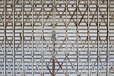 Close up the old rusty folding steel door with locked. Old vintage folding gate texture pattern. Metal expanded sliding gate backg Stock Photo
