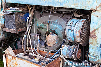 Close-up on an old rusty tractor or truck engine with a battery and oil drips during repair in a workshop. Auto service industry Stock Photo