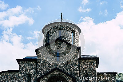 Close up of old stone church on background of blue sky with white clouds. Architecture of monastery from uneven Stock Photo