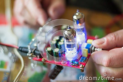Close up old tube amplifier in male hands. Process of testing music detail with voltmeter. Illuminated lamps sound plate Stock Photo