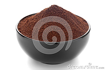 Close-Up of organic dark brown coffee granules in black ceramic bowl over white background Stock Photo