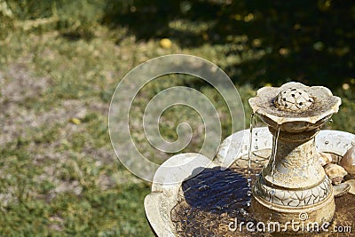 Rustic marble ornamental fountain with flowing and cascading water located in a garden Stock Photo