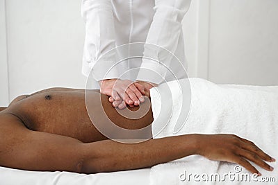 Close up of osteopath doing manipulative massage on african male abdomen on white background, copy space. Stock Photo