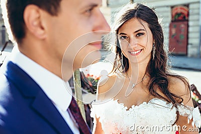 Close-up outdoor portrait of the young brunette bride with lovely sight and pretty smile looking in camera standing Stock Photo