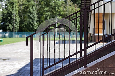 Close-up outdoors detail of short stone staircase with metal protective simple primitive metal fence and handrails on lit by brigh Stock Photo