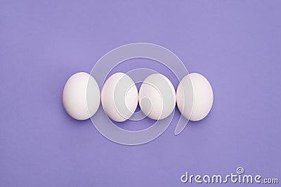 Close up overhead top view photo of four eggs in row with white shell isolated violet color background Stock Photo