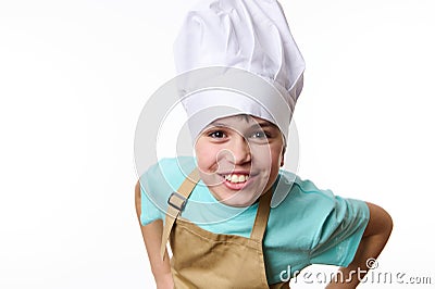 Smiling happy teenager boy - chef pastry, cook, baker confectioner wearing chef hat and beige apron, isolated on white Stock Photo