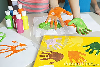 Close-up of paint covered hands and colorful handprints on papers Stock Photo