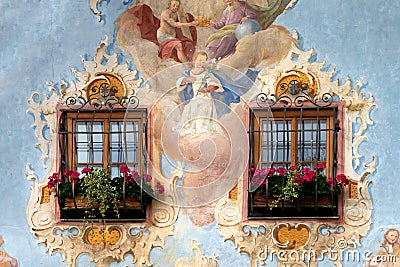 Close up of a painted facade with two wooden windows and geraniums on the windowsill Stock Photo