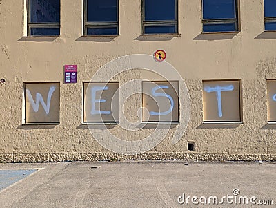 Close-up of a painted mural on the side of a building, the inscription reads "West" Editorial Stock Photo