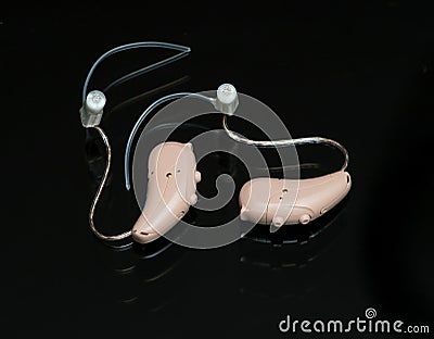 Close up of a pair of tiny modern hearing aids on black background Stock Photo