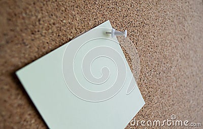 Close up of a pale green paper note on a cork Board, attached with a white pushpin. Copy space Stock Photo