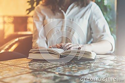 Close-up of paper book, notebook, diary on table in cafe. Businesswoman in white shirt sitting at table and reading book Stock Photo