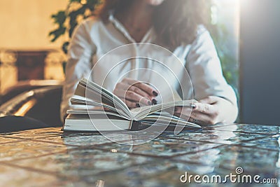 Close-up of paper book, notebook, diary on table in cafe. Businesswoman in white shirt sitting at table and reading book Stock Photo