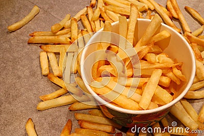 Close up on a paper cup with crispy golden French fries. Stock Photo