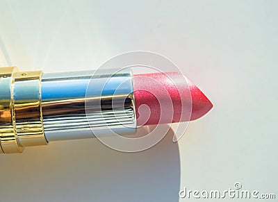 Close-up of a part of a golden tube of lipstick on a white background Stock Photo