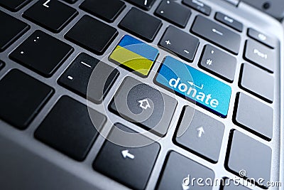 Close-up part of a laptop, black keyboard of a laptop computer, blue, yellow buttons of the Ukrainian flag with the word donate, Stock Photo