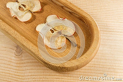 Close-up part of oblong wooden plate with apple chips on wooden background Stock Photo