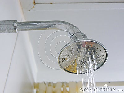 Close up of a partly clogged shower head in a bathroom, causing it to putting out so little water Stock Photo