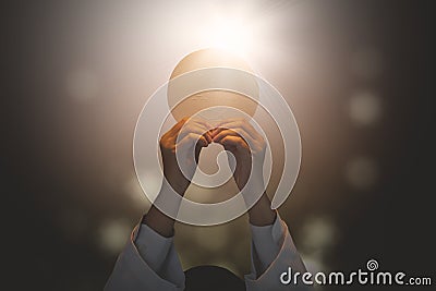 Pastor lifting a bright communion bread Stock Photo