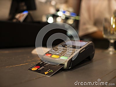 Close up payment machine on the table for paying bill by at table. wireless pos terminal with card Editorial Stock Photo