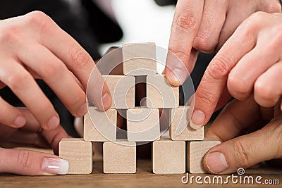 People Arranging Block On Pyramid Stock Photo