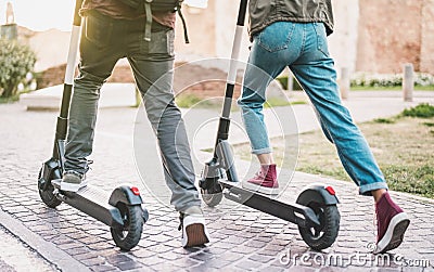 Close up of people couple using electric scooter in city park - Millenial students riding new modern ecological mean of transport Stock Photo