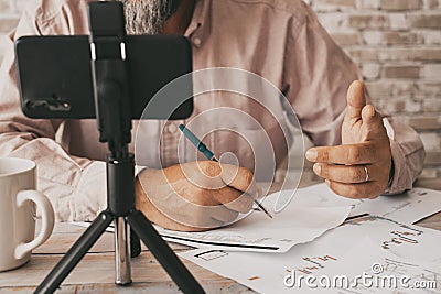 Close up of people doing online contents using phone and little tripod. Man writing on paper notes. Concept of online job and Stock Photo