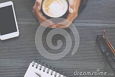 Close up people female sit hand holding cup coffee on desk table with book Stock Photo