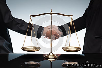 Close up of people shaking hands together in front of scale balance. Stock Photo