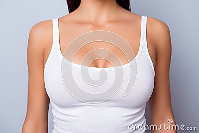 Close up of perfect lady`s chest with bronze skin in white singlet on light blue background Stock Photo