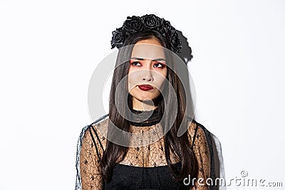 Close-up of perplexed asian woman in wicked witch costume, looking at upper left corner doubtful or indecisive, standing Stock Photo