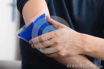 Person Applying Ice Gel Pack On An Injured Elbow Stock Photo