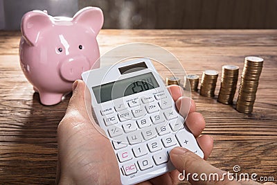 Person Calculating On Calculator With Piggybank And Coin Stacked Stock Photo