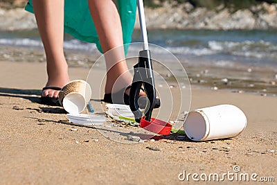 Close Up Of Person Collecting Plastic Waste From Polluted Beach Using Litter Picker Stock Photo