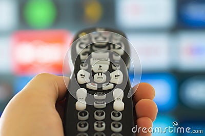 Close up of a person holding a control remote with a television screen on the background Stock Photo
