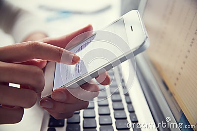 Close Up Of Person At Laptop Using Mobile Phone Stock Photo