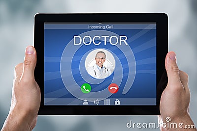 Person`s Hand Holding Tablet With Doctor`s Incoming Call Stock Photo