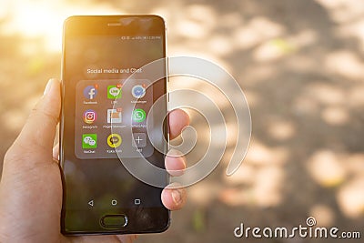 Close up of person`s hand holds smart phone with social media application icons show on screen. Editorial Stock Photo