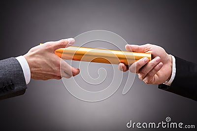 Person Passing Baton To Businessperson Stock Photo