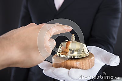 Person`s Hand Ringing Service Bell Hold By Waiter Stock Photo