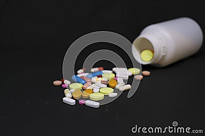 Close up of pharmaceutical medical pills next to a drug bottle in a dark background Stock Photo