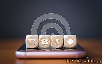 Close-up of a phone, email, chat and post icons wooden dice arranging in a row on mobile phone Stock Photo