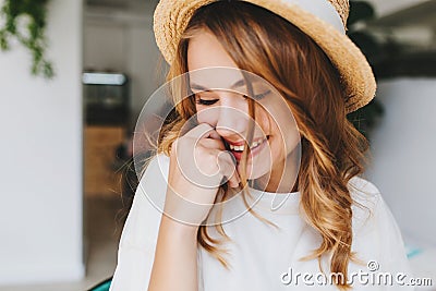 Close-up photo of amazing happy girl with pale skin shy laughing and cover face with hand. Indoor portrait of ecstatic Stock Photo