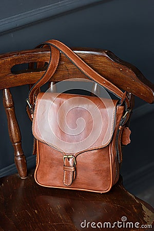 close-up photo of brown messanger leather bag on a wooden chair Stock Photo