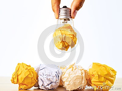 Close up photo of crumbled colorful paper and light bulb in the same frame as a symbol of persistance, perseverance Stock Photo