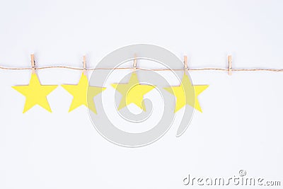 Close up photo of four of five golden start hanging on thread attached with little pings isolated white color background Stock Photo